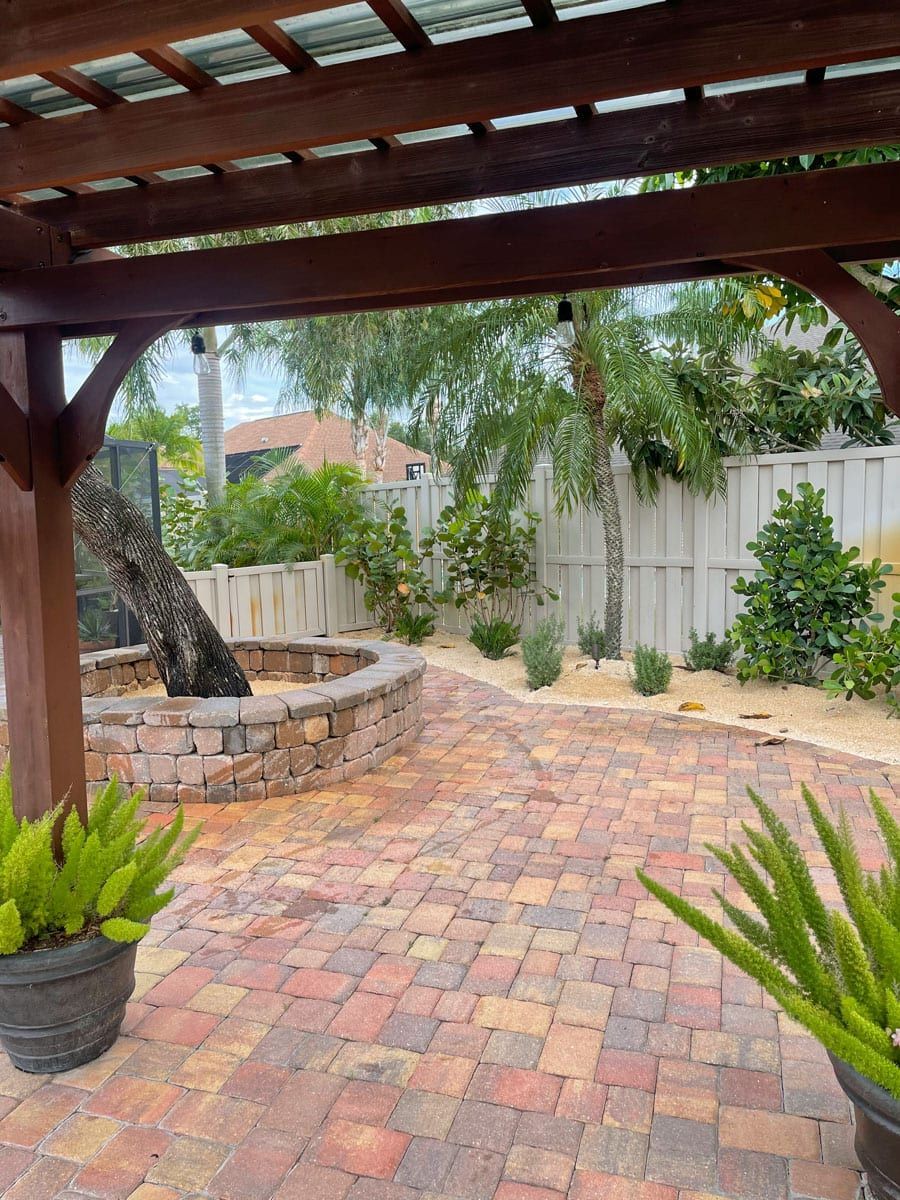There is a fire pit in the middle of the patio under a pergola.
