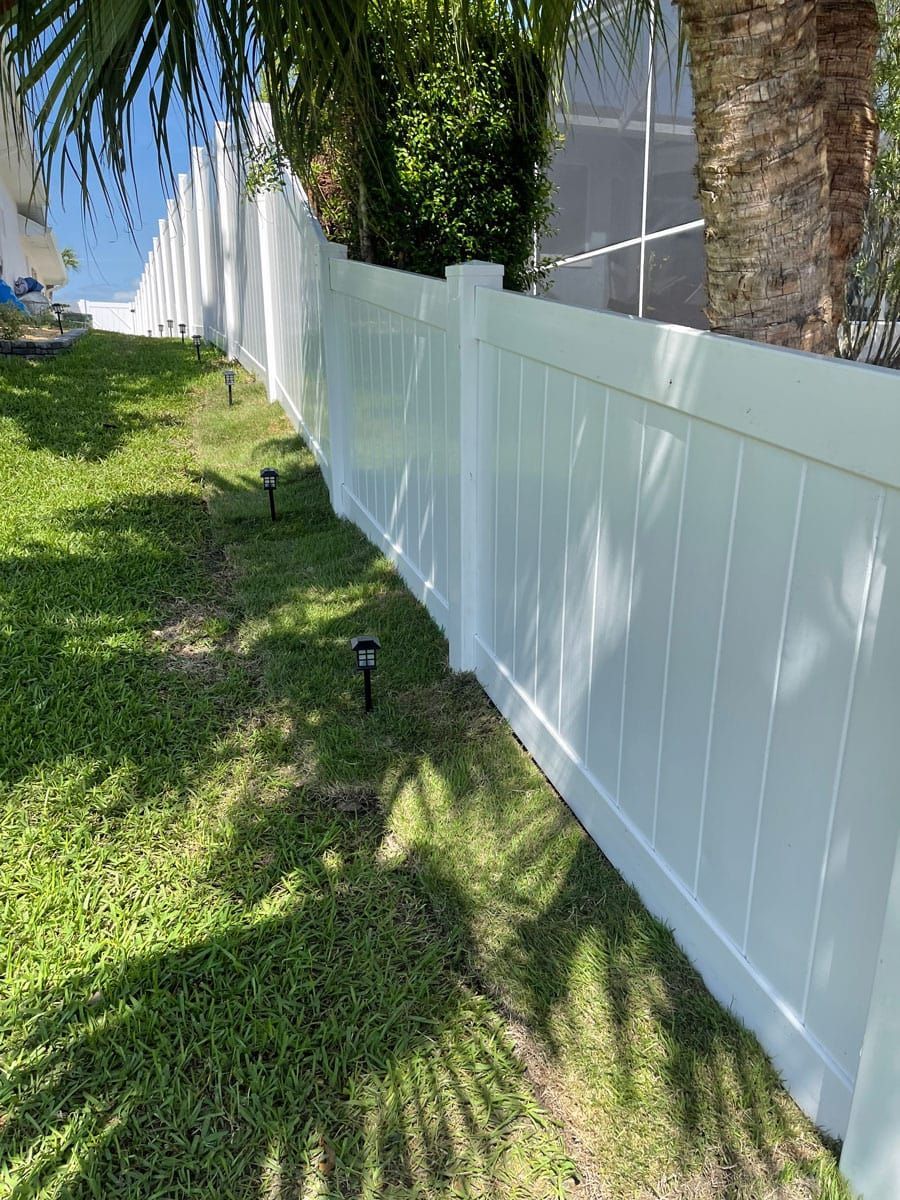 A white fence is sitting in the middle of a lush green yard.