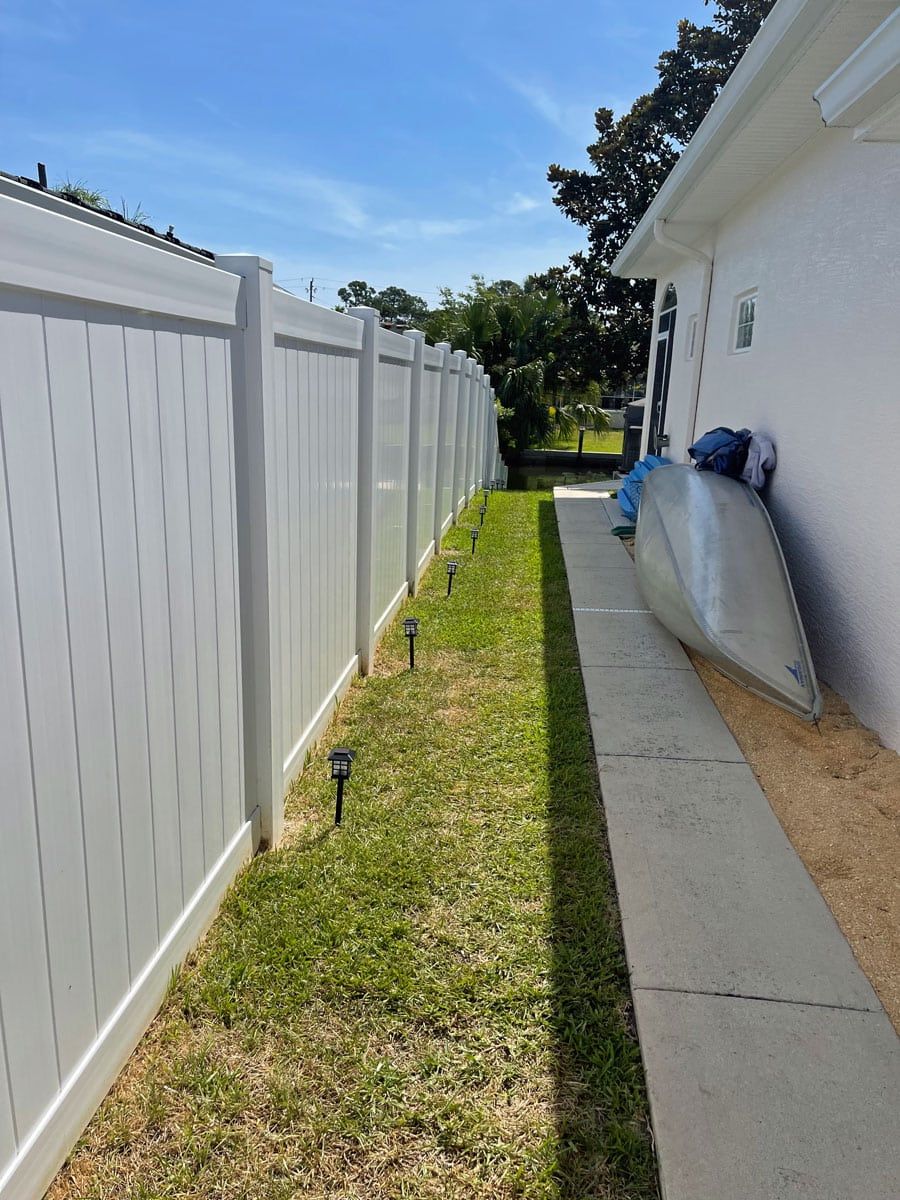 A white fence along a sidewalk next to a house.