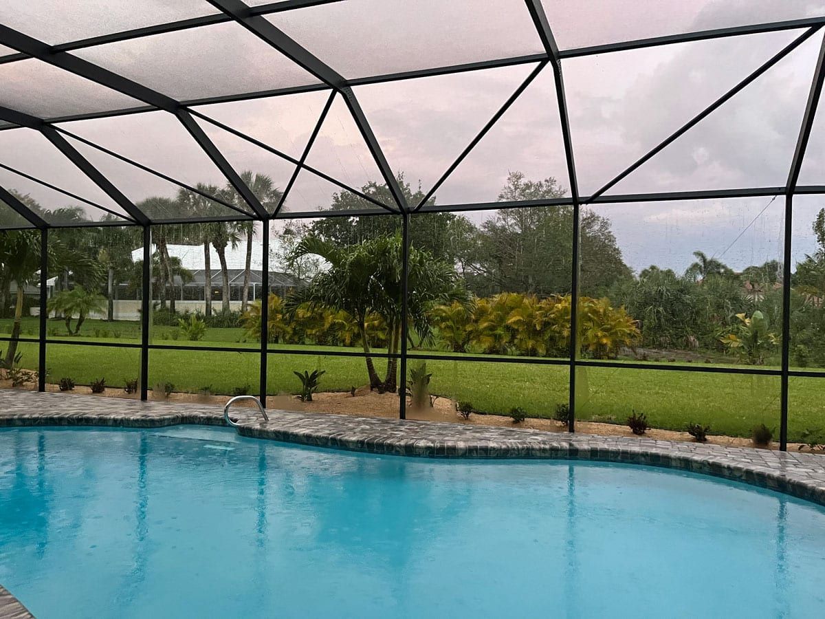 A large swimming pool with a screened in area in the backyard.