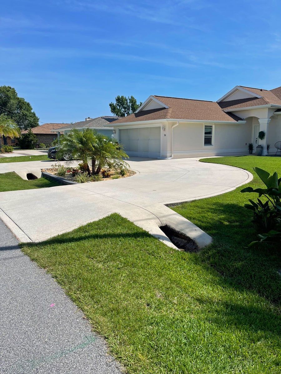 A white house with a lush green lawn and a driveway leading to it.