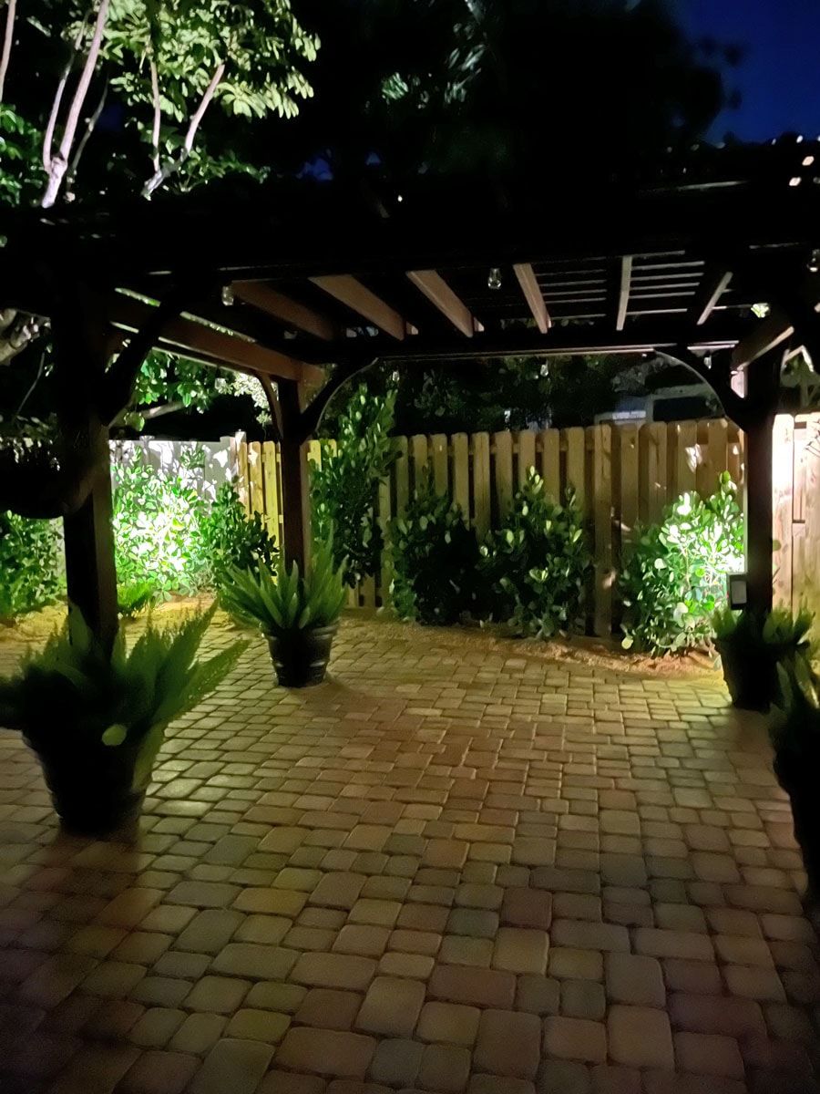 A brick walkway under a pergola at night