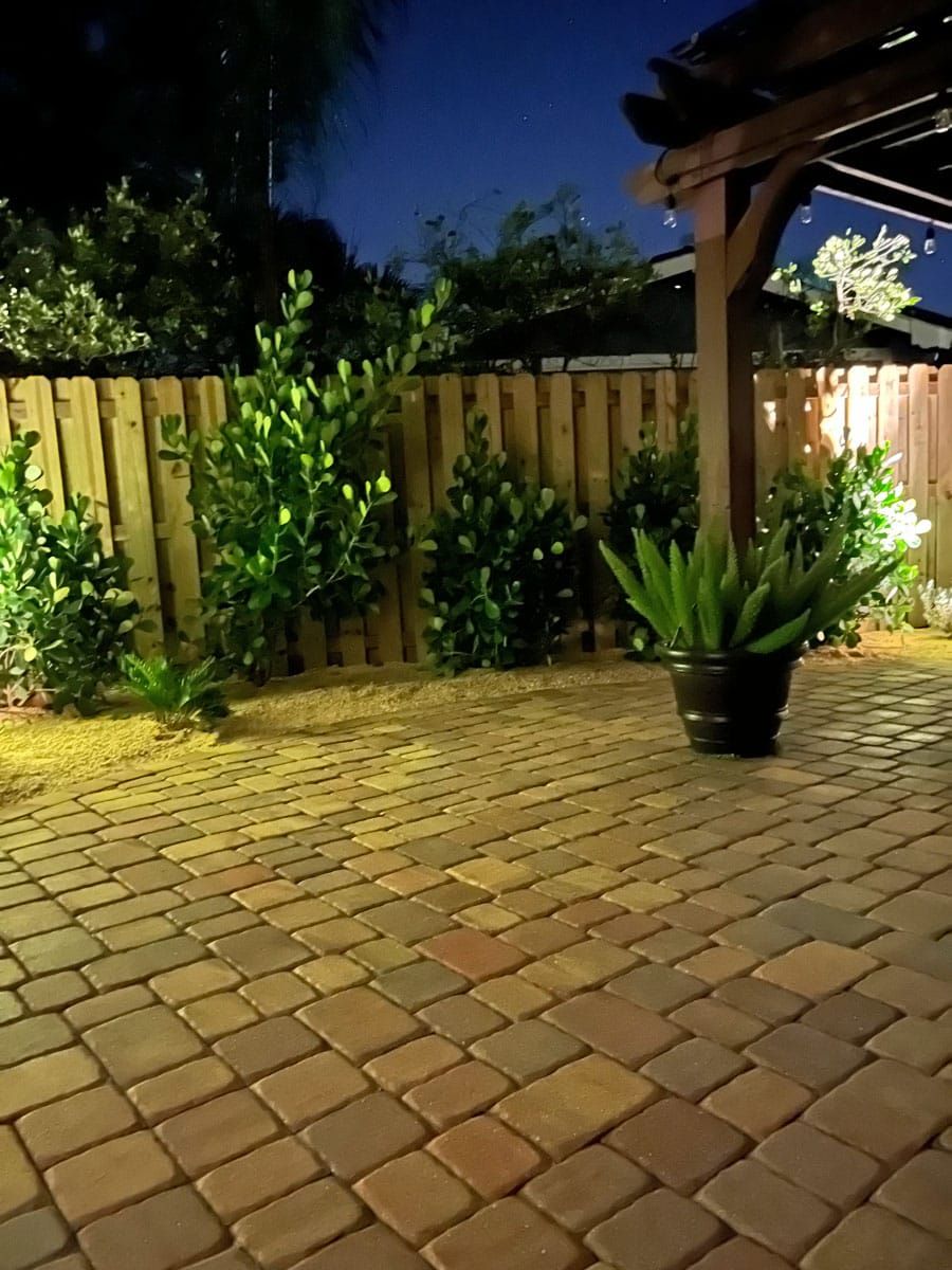 A brick patio with a wooden fence and a potted plant