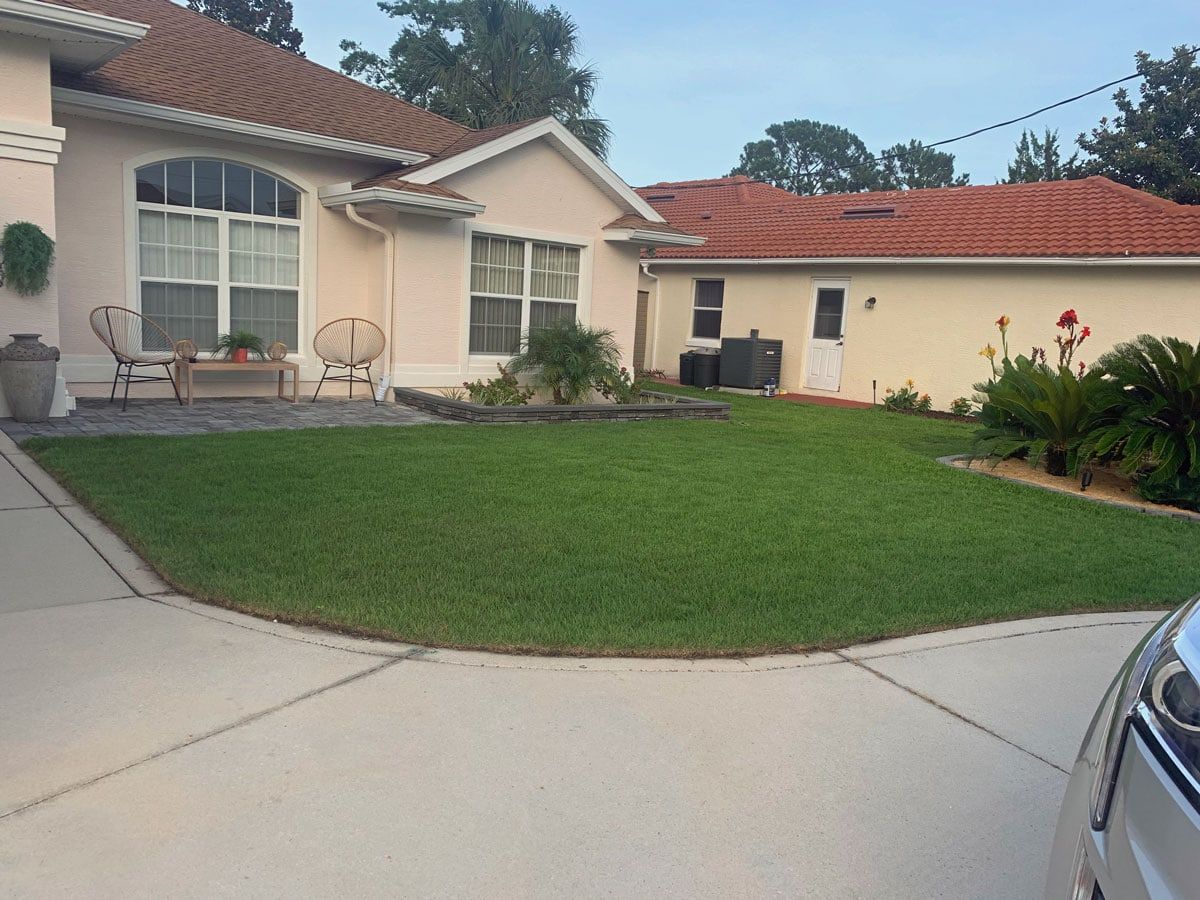 A car is parked in front of a house with a lush green lawn.