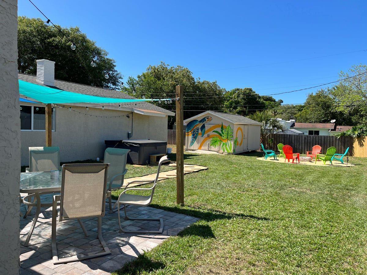 A backyard with a table and chairs and a green umbrella.