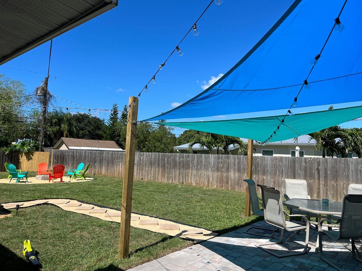 A backyard with a table and chairs under a blue umbrella.