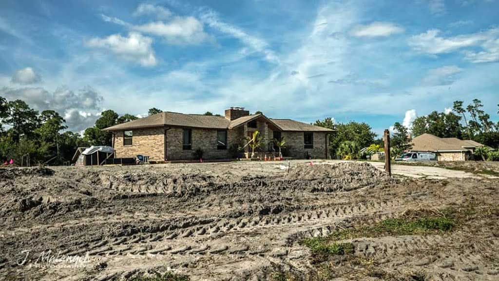 A large house is sitting in the middle of a dirt filled yard.
