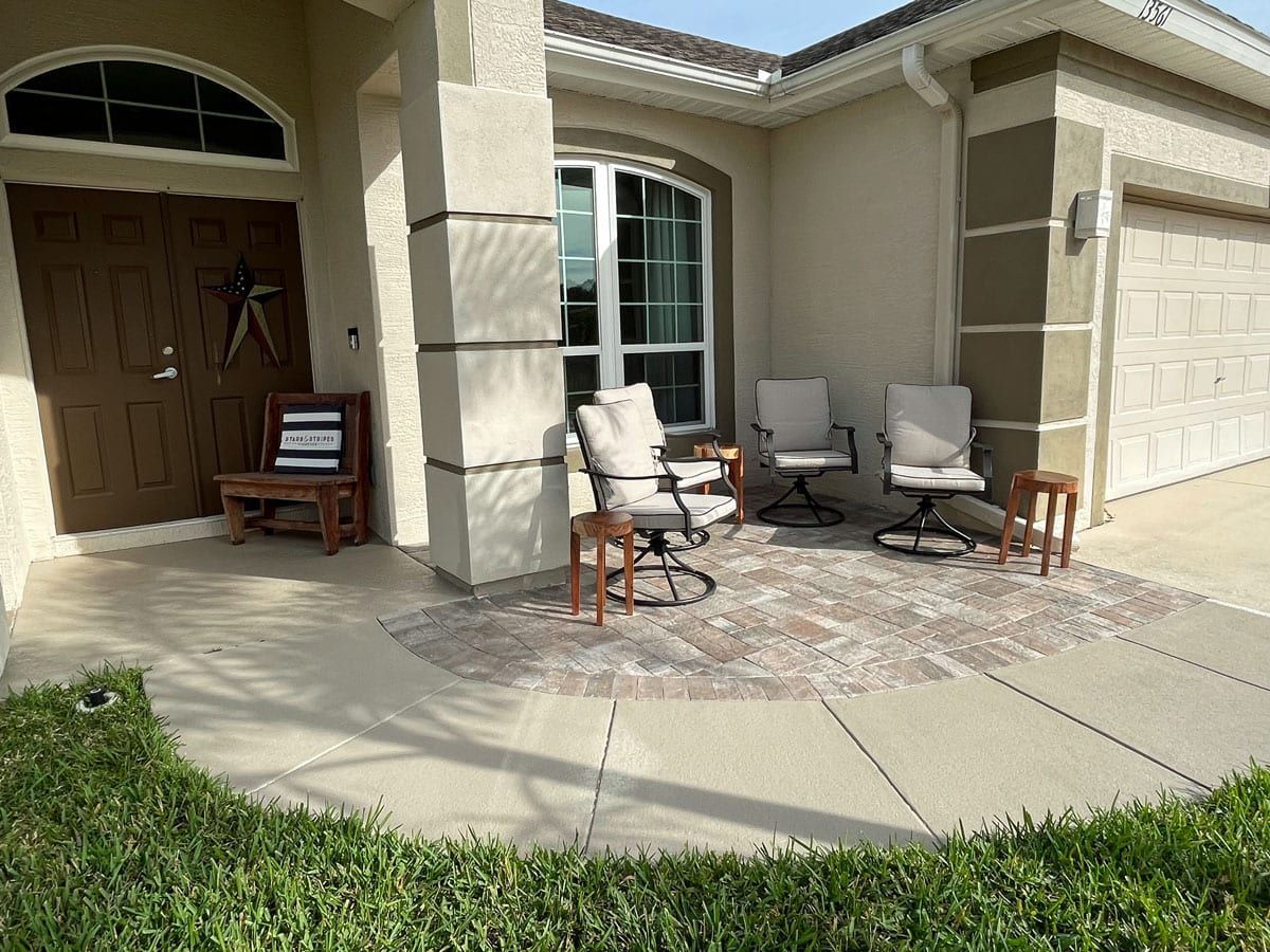 A patio with chairs and tables in front of a house.