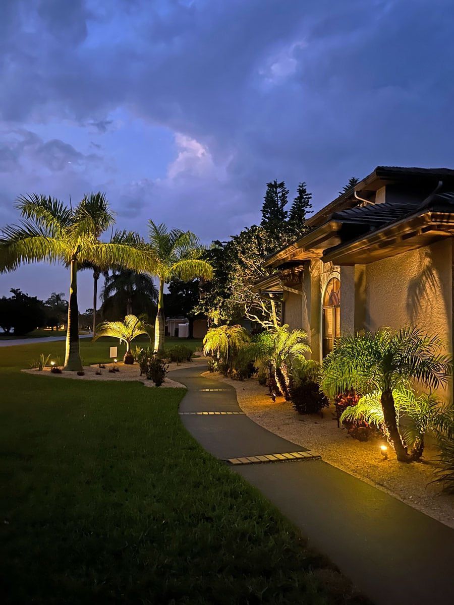 A house with a walkway leading to it is lit up at night.