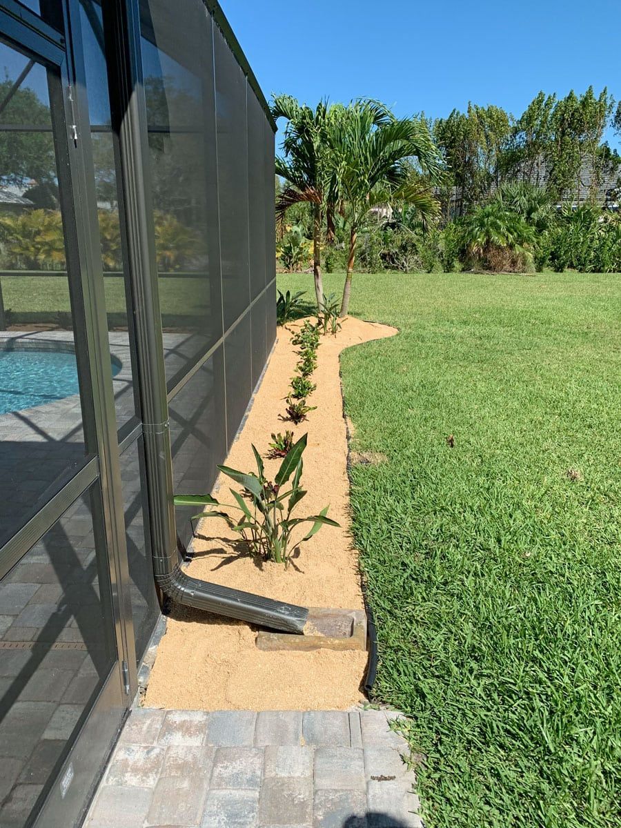 A backyard with a screened in pool and a sidewalk leading to it.