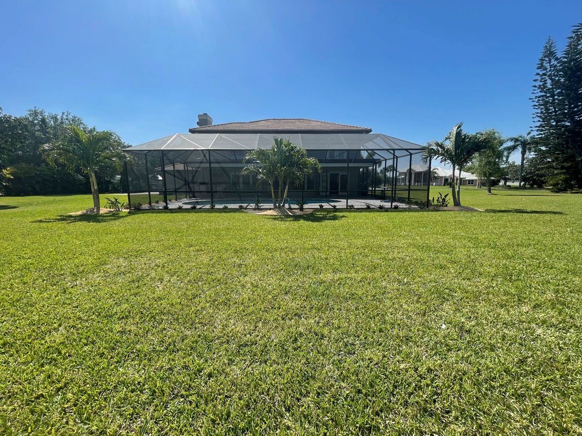 A large house is sitting in the middle of a lush green field.