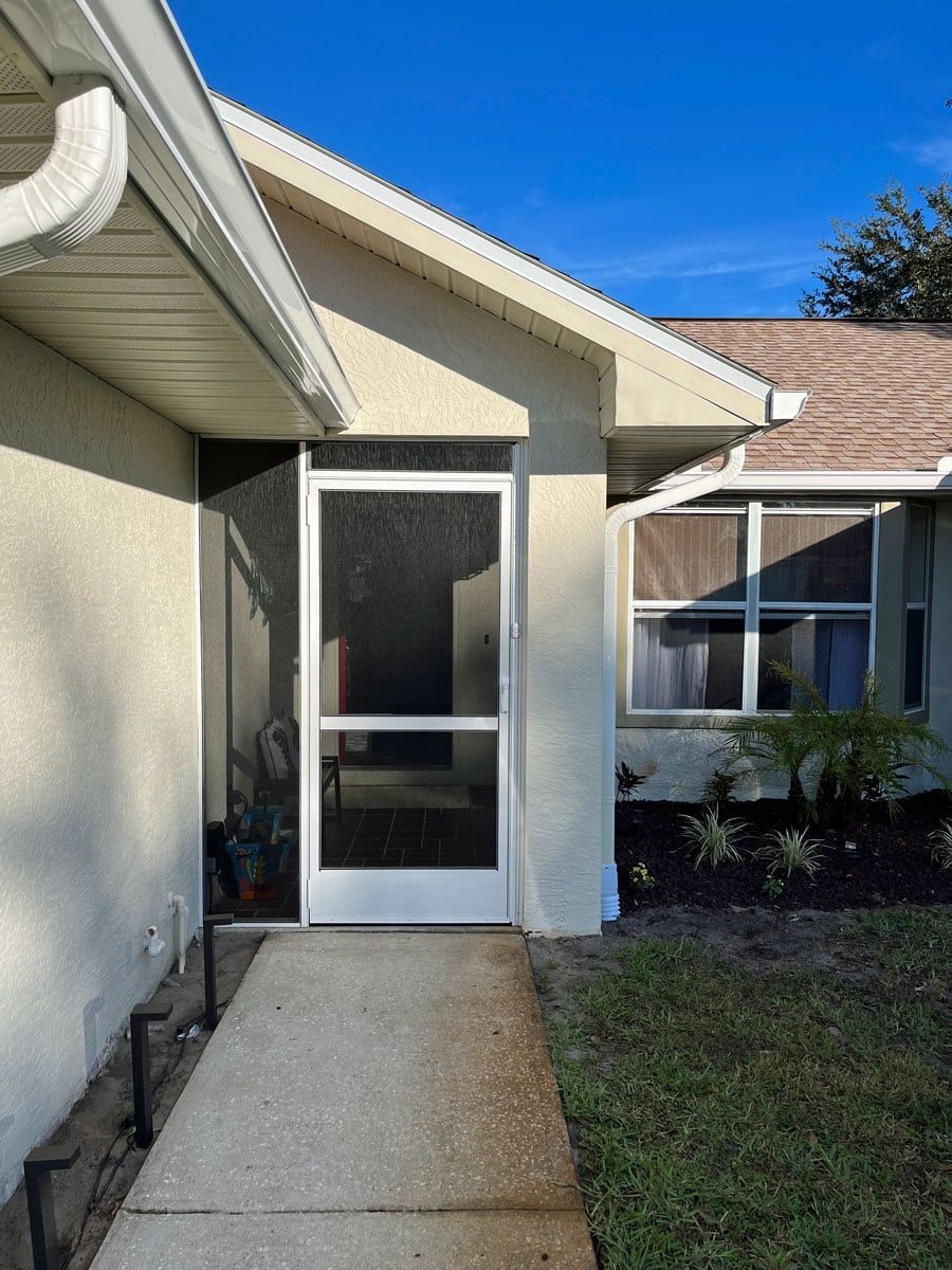 A house with a screened in porch and a walkway leading to it.