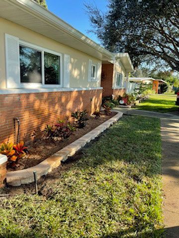 A house with a lot of plants in front of it.