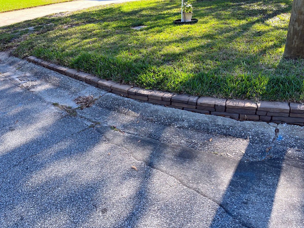 A brick curb on the side of a road next to a grassy area.