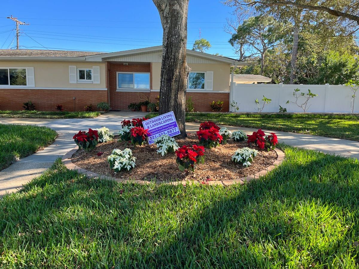 A yard with flowers and a sign in front of a house.