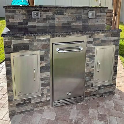 A stainless steel dishwasher is built into a brick wall.