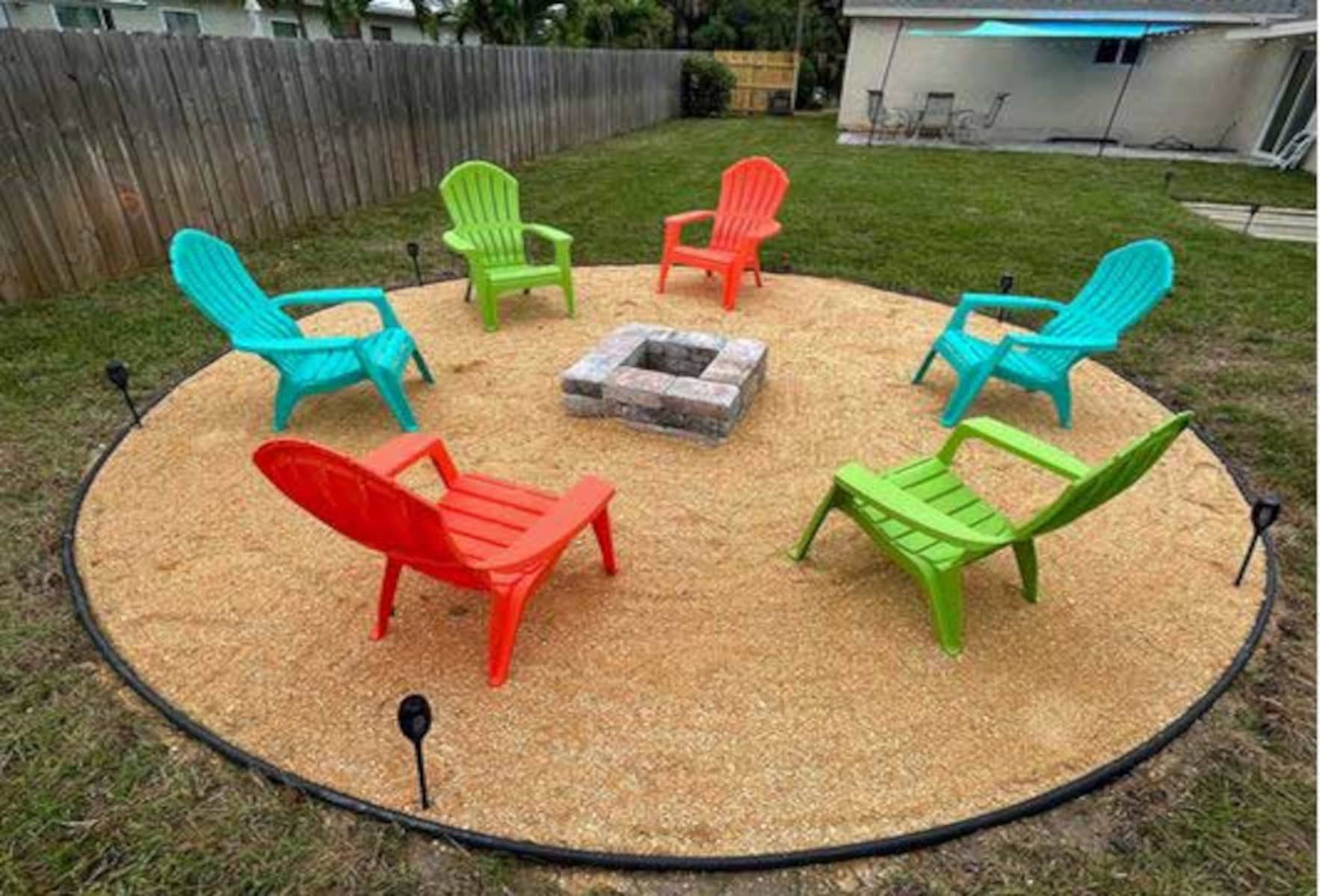 A group of colorful chairs are sitting around a fire pit.