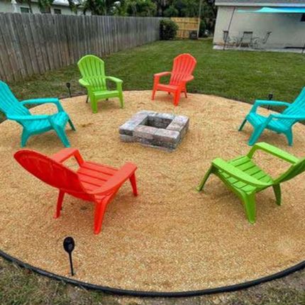 A group of colorful chairs are sitting around a fire pit.