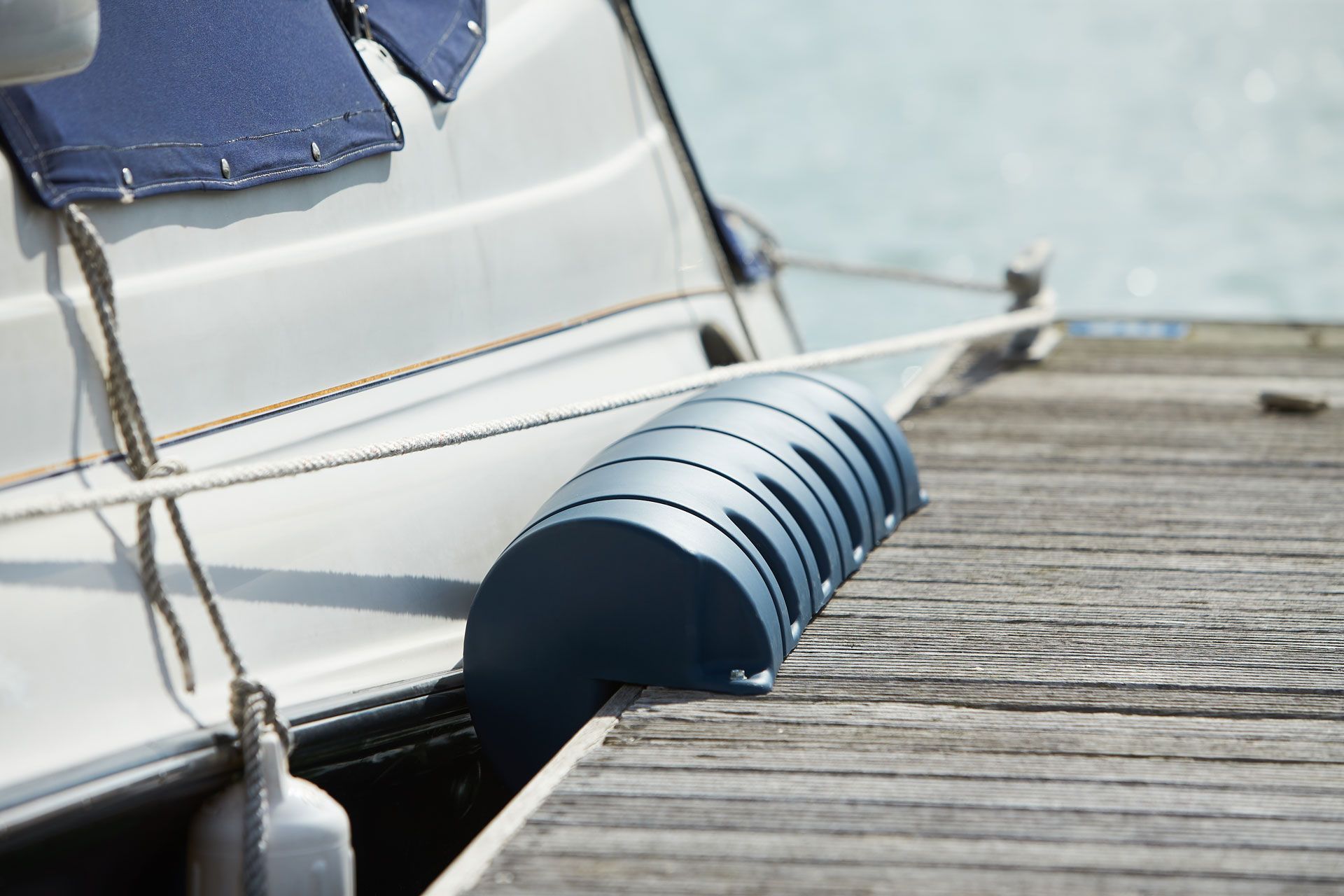 Blue boat fender between a white boat and wooden dock.