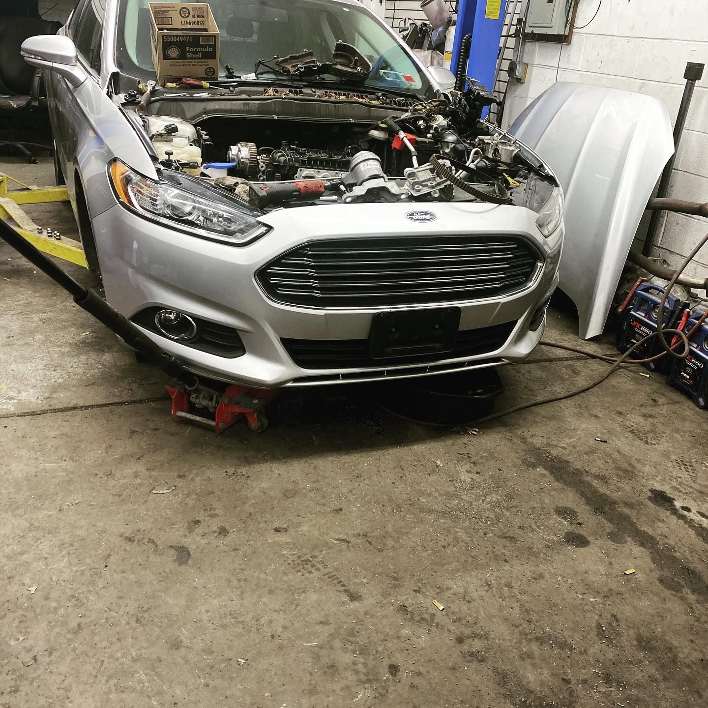 A ford fusion is being repaired in a garage