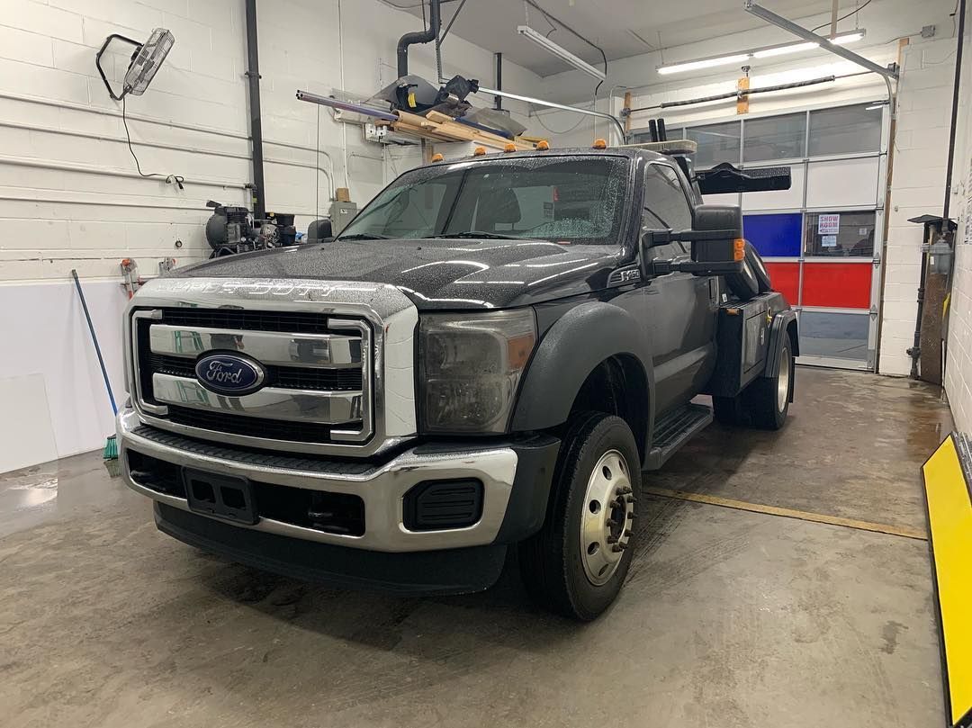 A ford tow truck is parked in a garage.