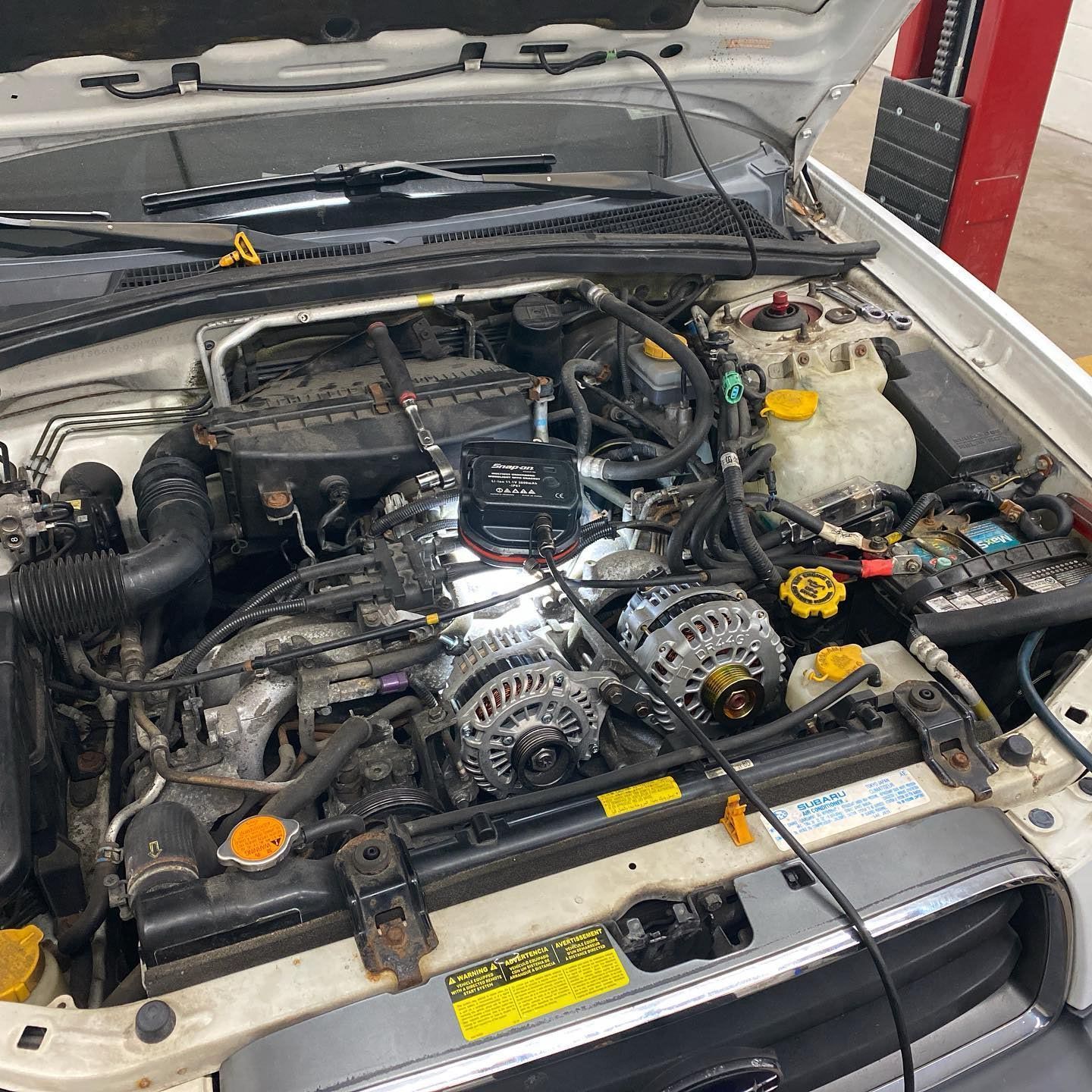 The engine of a subaru is shown with the hood open.