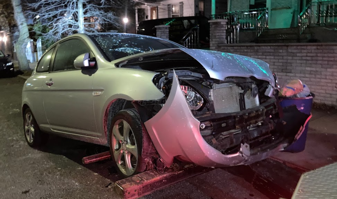 A car with a broken bumper is parked on the side of the road.