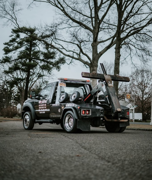 A black tow truck is parked on the side of the road.
