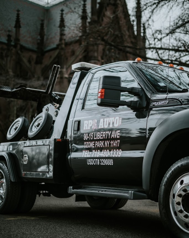 A black tow truck is parked on the side of the road.