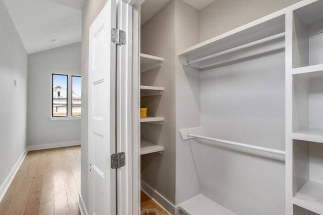 A partially open white closet door reveals white shelving and a clothing rod, with a glimpse of a room beyond.