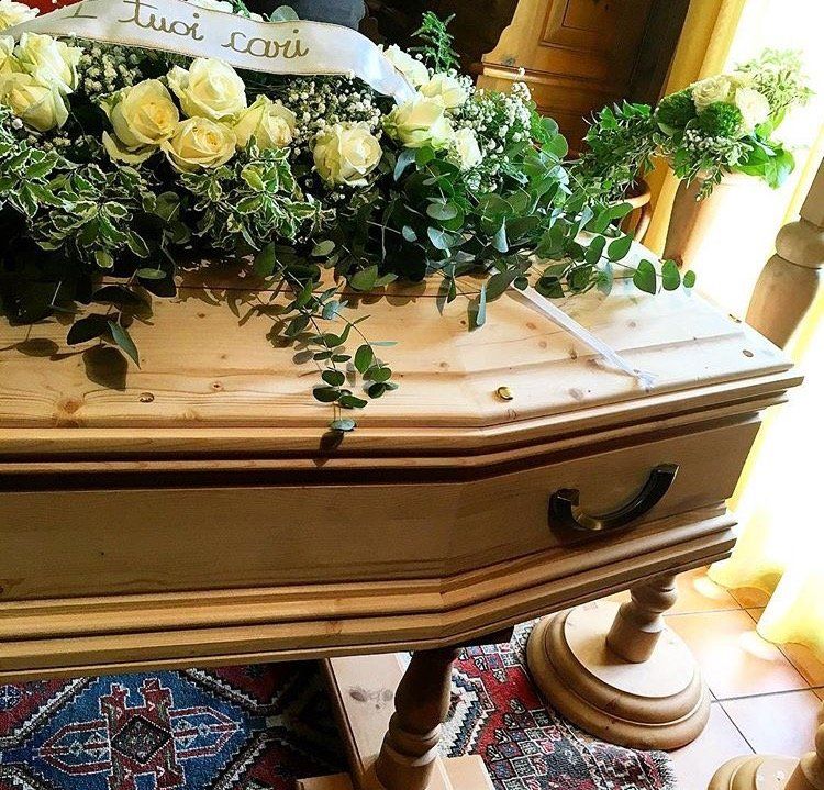 Una bara di legno con fiori e un nastro con la scritta