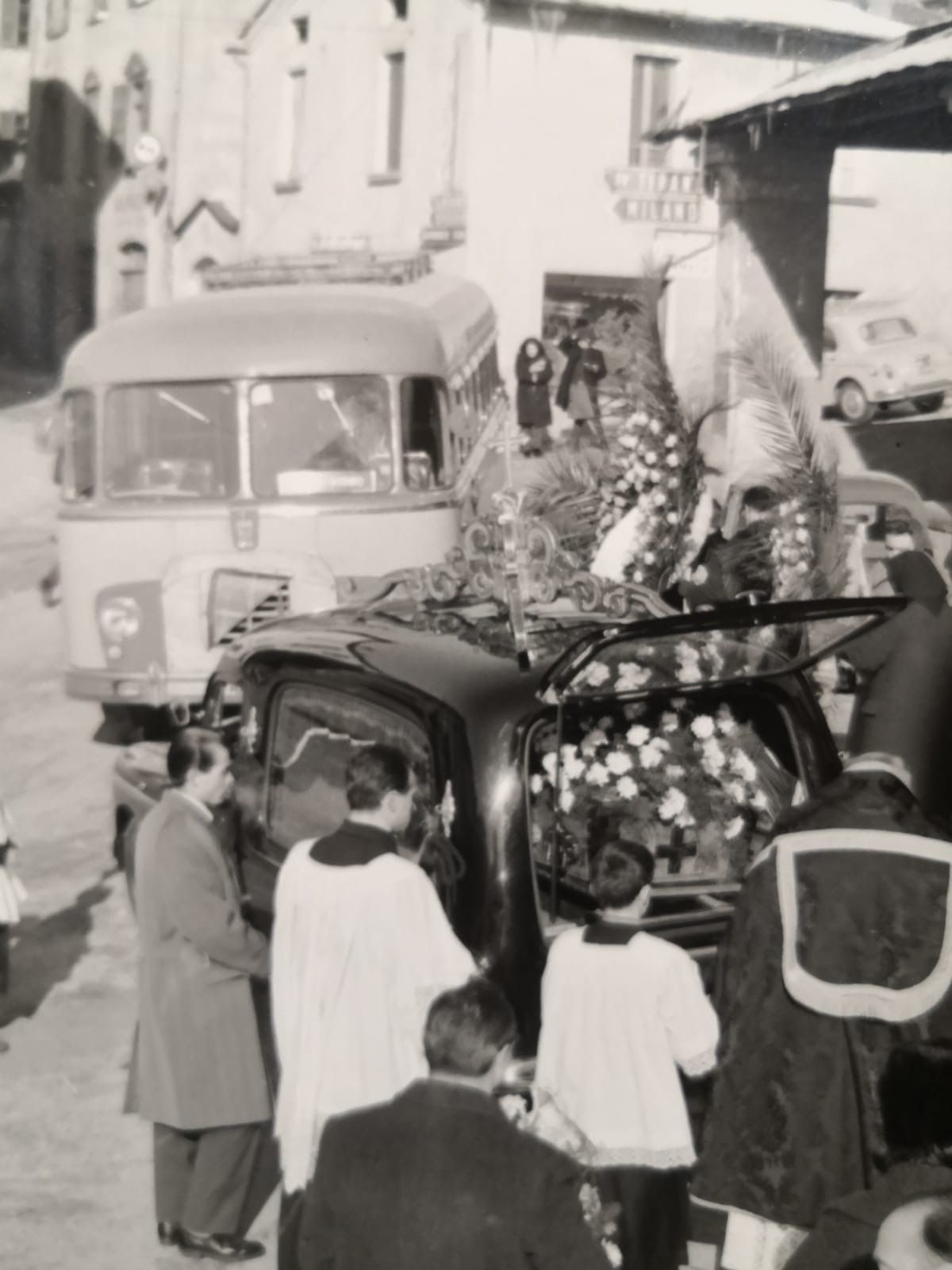 Un gruppo di persone è in piedi attorno a un'auto con dei fiori sul retro.