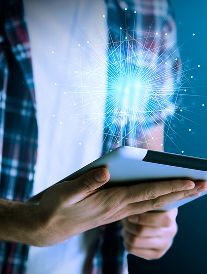Person holding tablet, with bright blue light emanating from it.