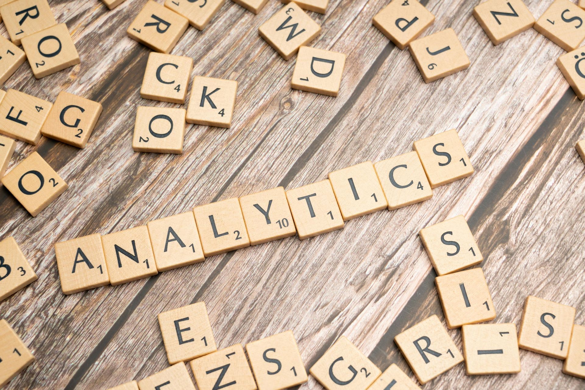 Scrabble tiles arranged to spell 'ANALYTICS' on a wooden surface, symbolizing data analysis and predictive capabilities in healthcare.