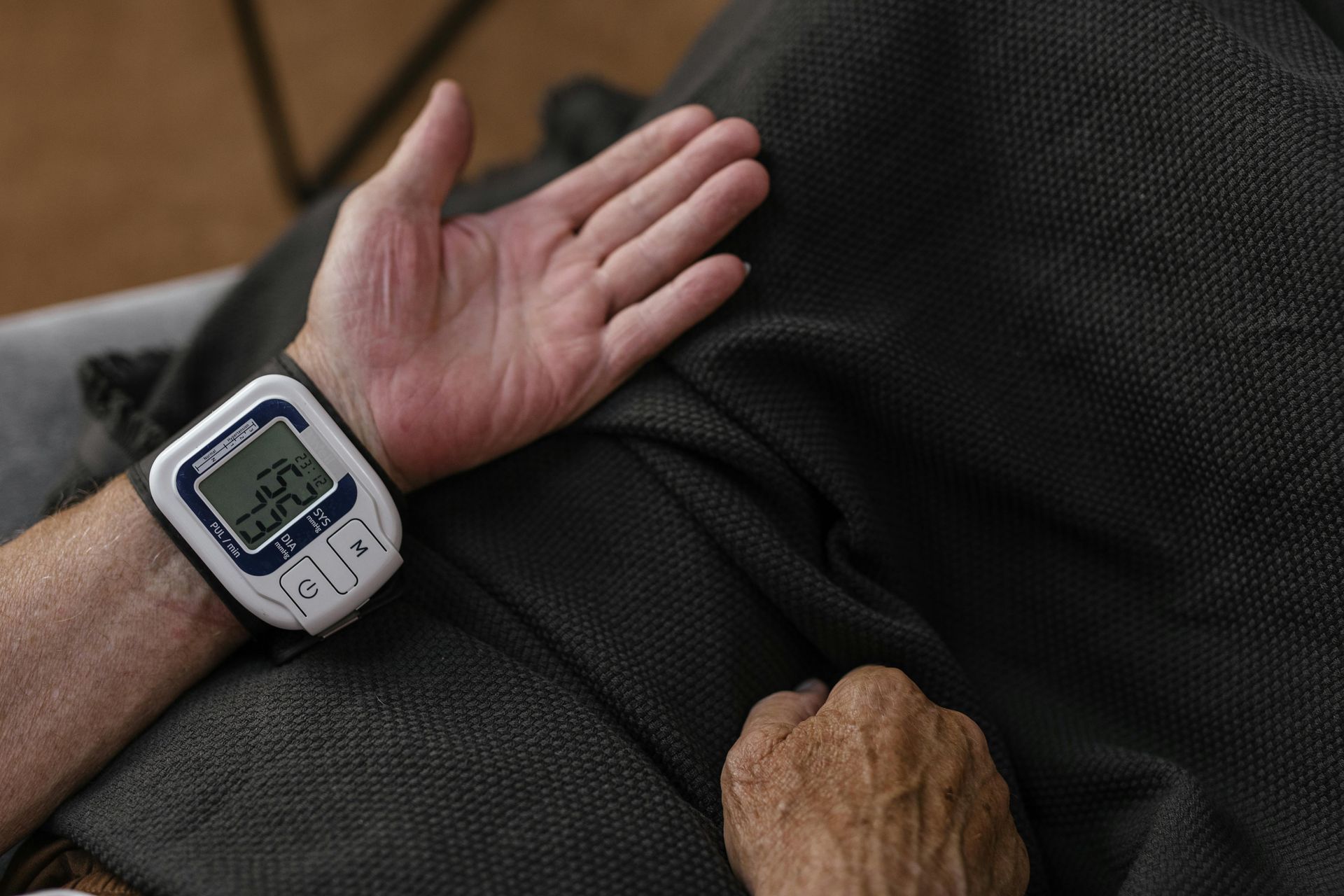 Hand wearing a digital blood pressure monitor, illustrating AI-enhanced patient monitoring in telehealth for chronic condition management.