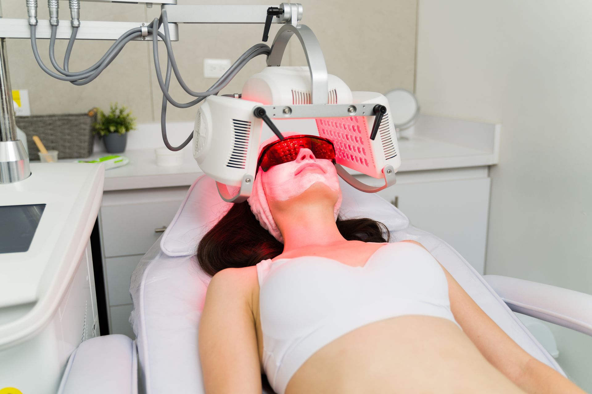Woman receiving LED light therapy in a spa setting, wearing protective eyewear.