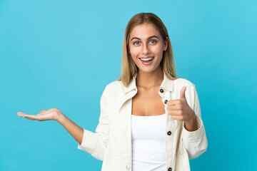 A woman is holding something in her hand and giving a thumbs up.