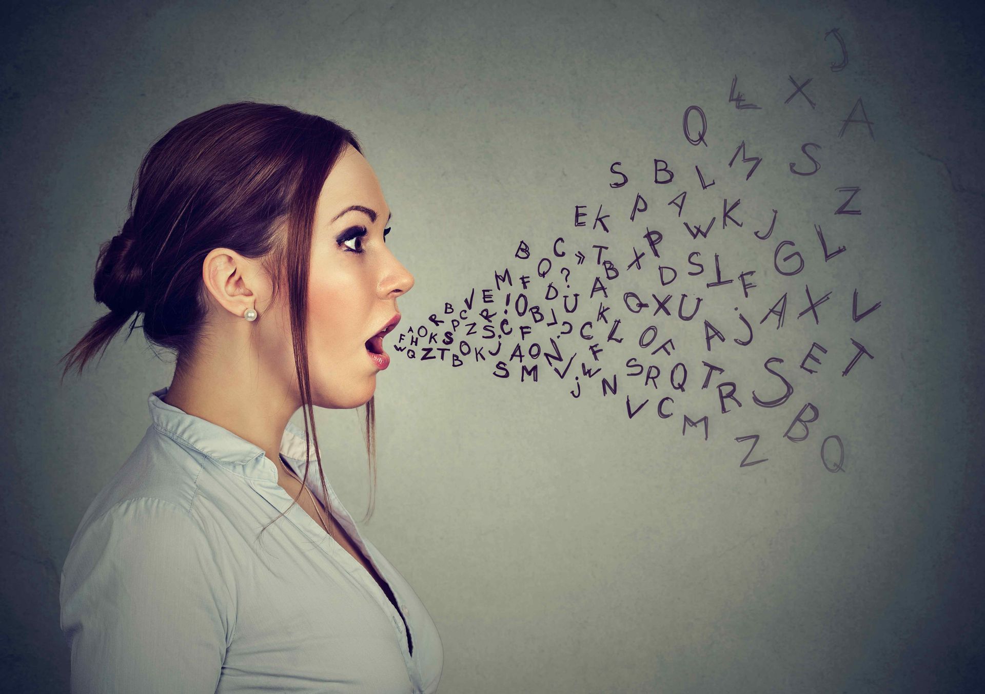 A woman is talking with letters coming out of her mouth.