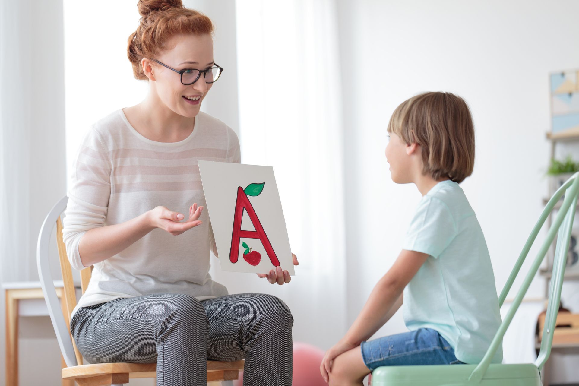 A woman is sitting in a chair holding a card with the letter a on it - New City, NY - A & T Certified
