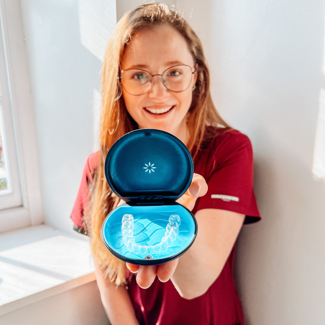 Smiling welcoming dental nurse holding clear invisible brace