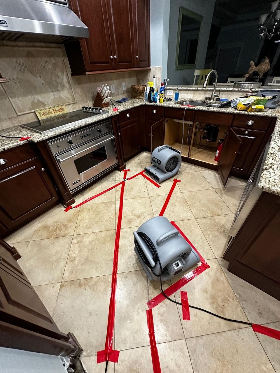 Two fans are sitting on the floor of a kitchen.