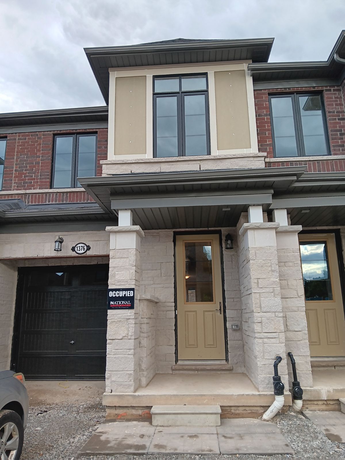 Townhouse exterior with beige and brick facade, front door and attached garage.