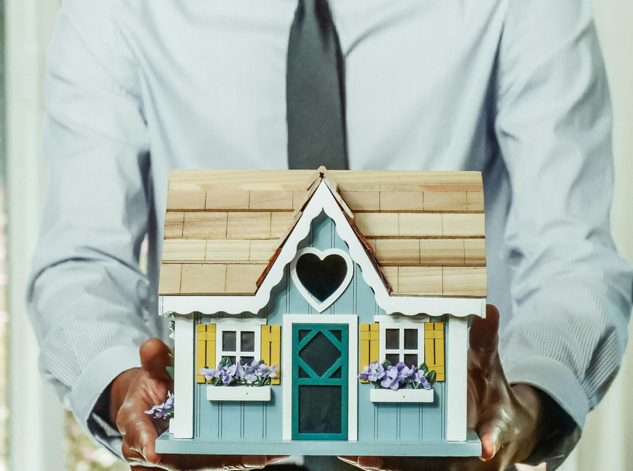 Man holding a small model house for real estate contact.