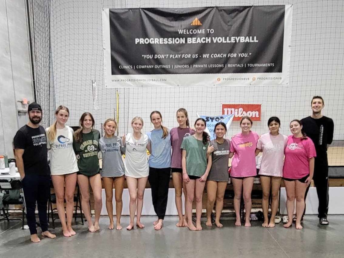 A group of people standing in front of a banner that says progression beach volleyball