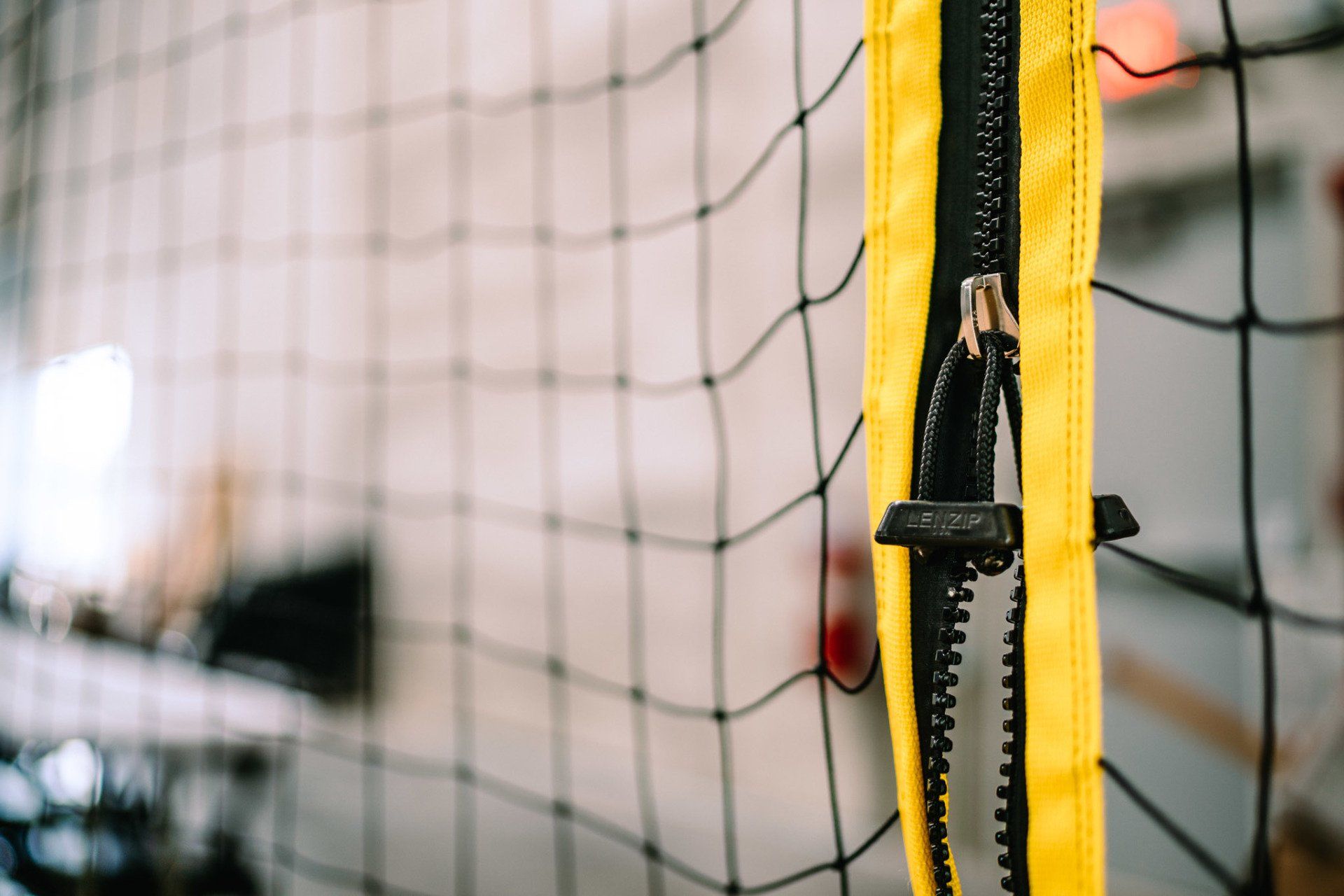 A close up of a yellow zipper on a volleyball net.
