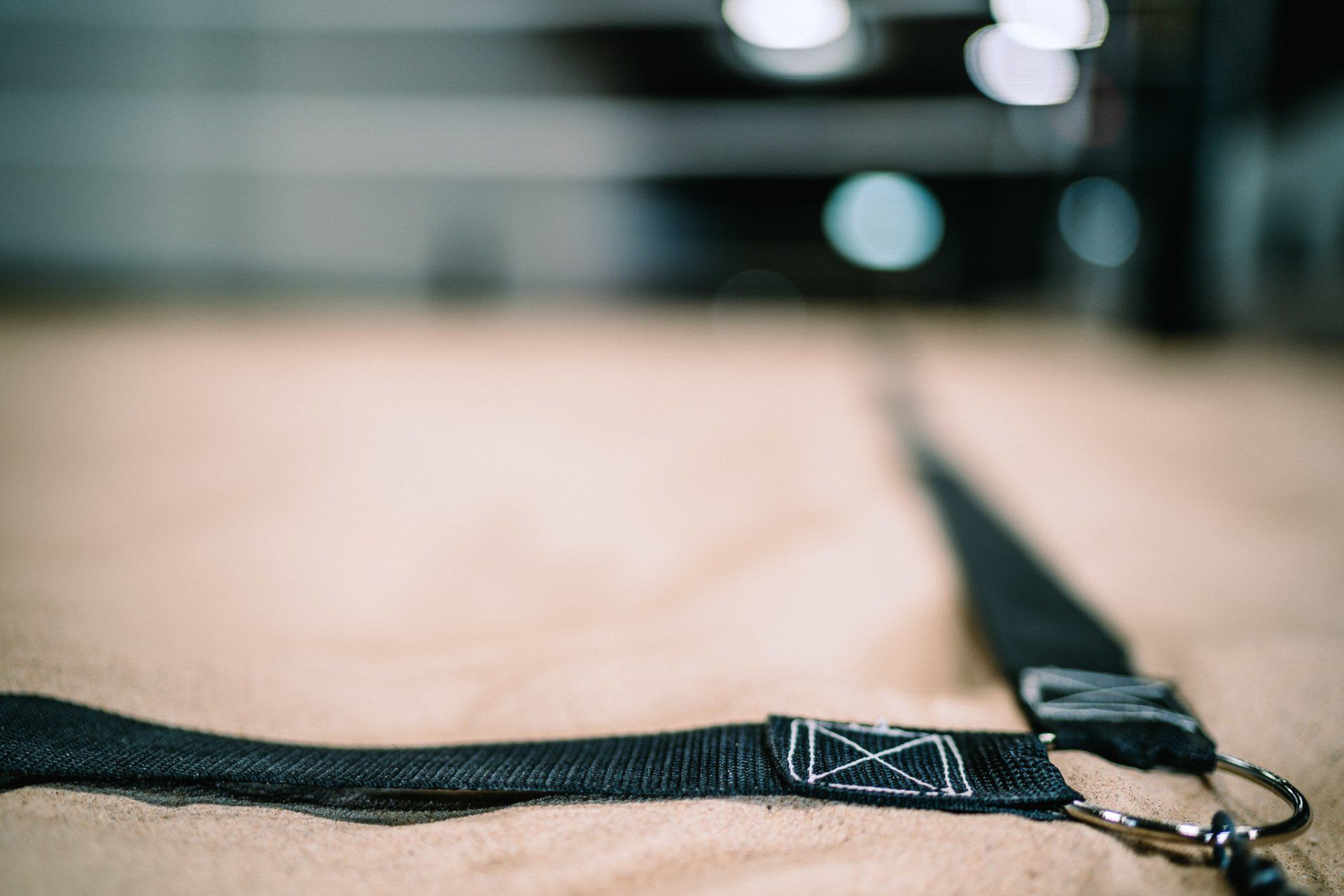 Black strap with a silver clasp on a tan surface, beach volleyball court