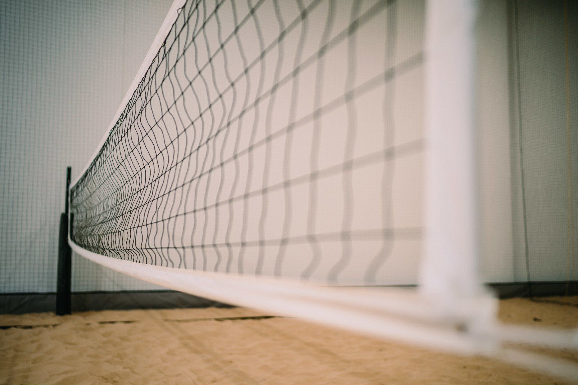 A volleyball net is sitting on top of a sandy court.