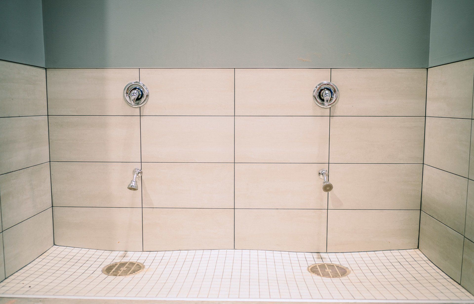A bathroom with two showers and a tiled floor.