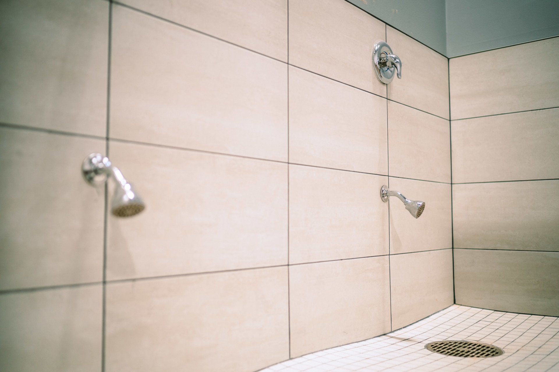 A bathroom with two showers and a tiled floor.