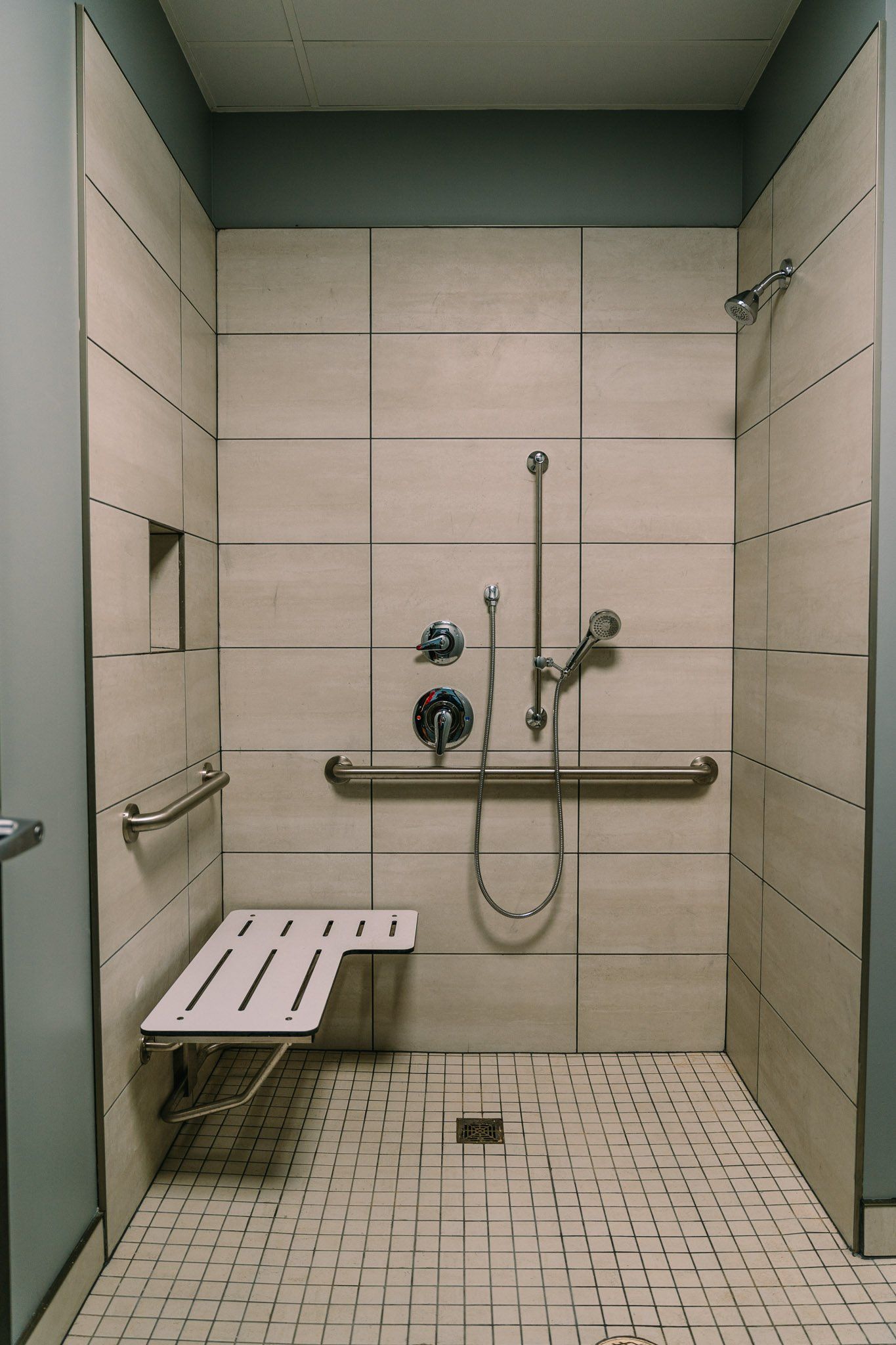 A walk in shower with a bench and handrails
